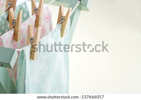 Closeup of pastel color laundry drying on vintage wooden drying rack with copy space