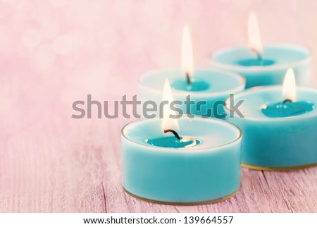 Blue burning candles on romantic pink vintage wooden background with blurred boked for copy space