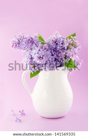 White vase with a bouquet of purple lilac spring flowers