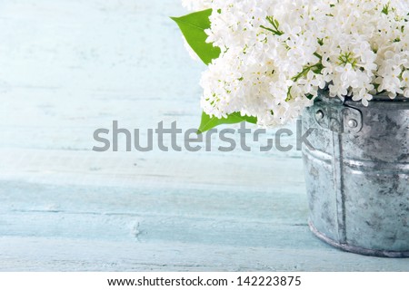 Bouquet of white lilac spring flowers in a wooden blue vase on light shabby chic background