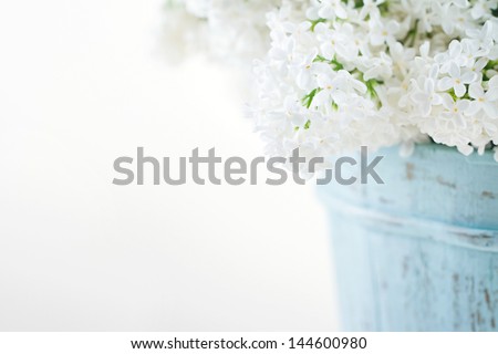 Bouquet of white lilac spring flowers in a wooden blue vase on light shabby chic background