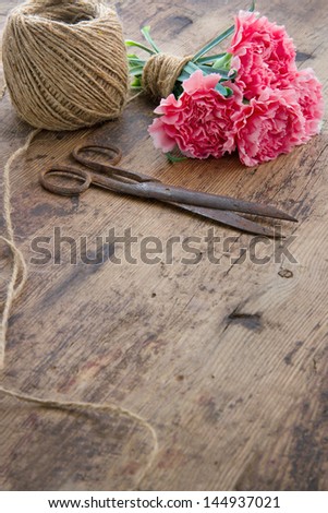 Bouquet of pink carnation flowers with old rusty antique scissors and ball of brown twine