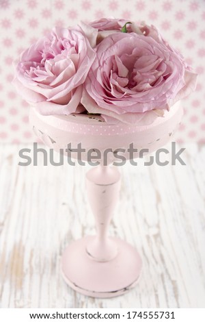Pink roses in a wooden pastel color vase on vintage white wooden shabby chic background