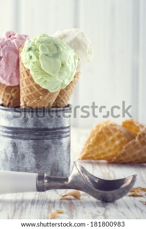 Pink and green ice cream cones with an old metal scoop on wooden rustic background with vintage hazy editing
