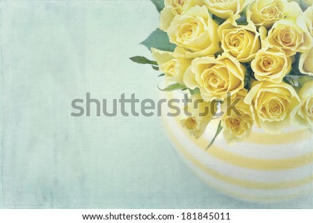 Striped vase with a bouquet of yellow spring roses on light blue vintage textured background