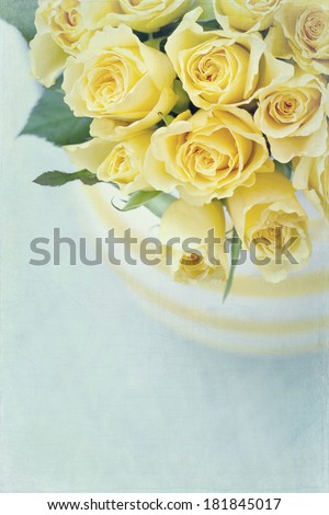 Striped vase with a bouquet of yellow spring roses on light blue vintage textured background