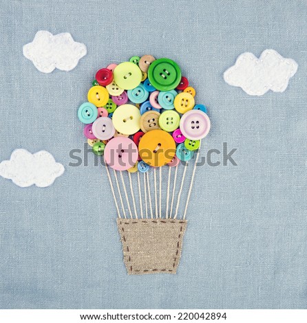 Handmade crafts of hot air balloon made of multicolored buttons on light blue linen textile background