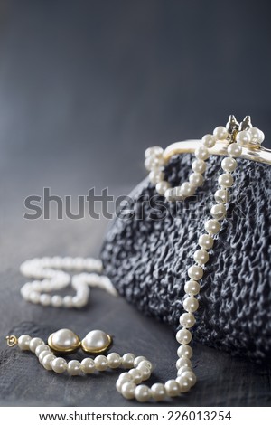 Old elegant vintage handbag from the 1950\'s with luxury pearls on black background for copy space