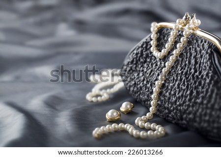 Old elegant vintage handbag from the 1950\'s with luxury pearls on black background for copy space