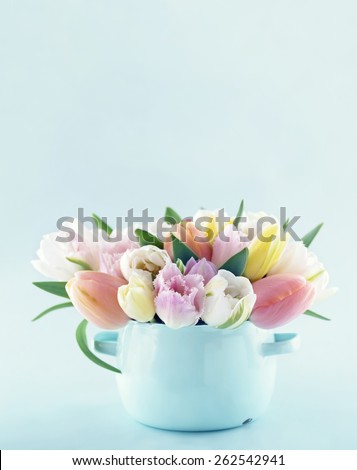Bouquet of spring tulips in a vintage vase on light blue pastel background with copy space
