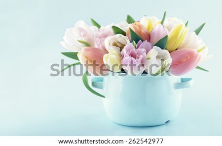 Bouquet of spring tulips in a vintage vase on light blue pastel background with copy space