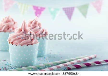 Pink frosted cupcakes on light blue background