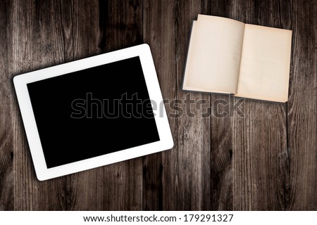 tablet computer and book  on old wooden table