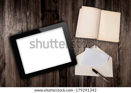 tablet computer and book with letter on old wooden table