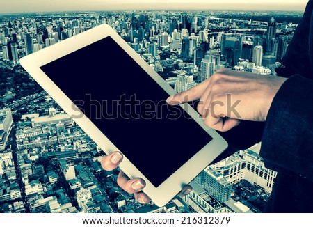 tablet in the hands of women on a city background in vintage style