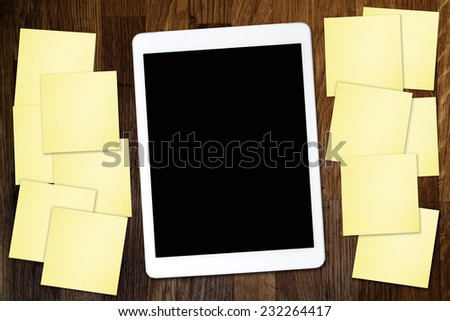 Digital tablet computer with sticky note paper and cup of coffee on old wooden desk. Simple workspace or coffee break with use of web .