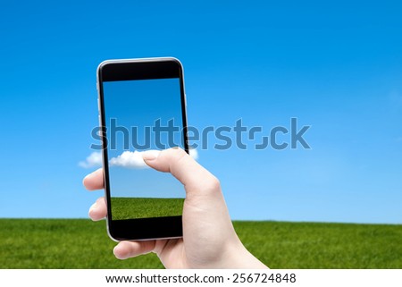 Phone in the hands of the meadow and sky in the background