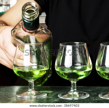Barman making cocktail.Several glasses of absinthe.