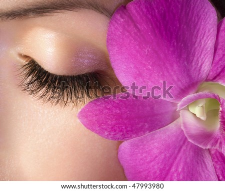 Woman eye with extremely long eyelashes and pink flower