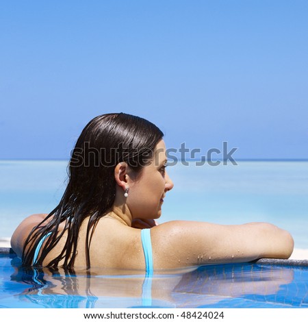 Woman enjoying sunny day at the swimming pool near the ocean