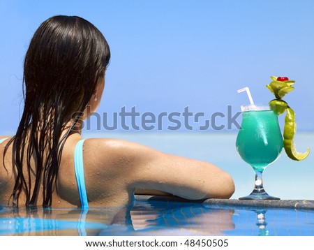 Woman enjoying sunny day at the swimming pool near the ocean