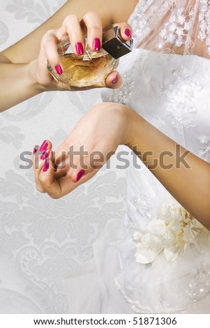 Bride spraying perfume on her wrist. Focus on hand with perfume bottle.
