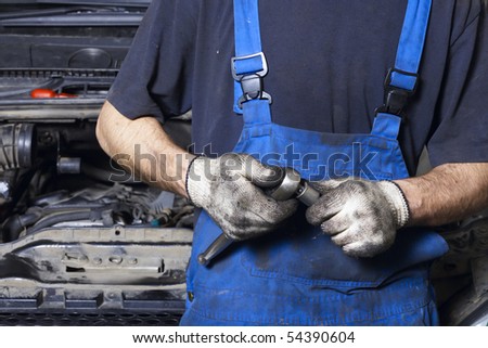 Auto mechanic in uniform holding work tool