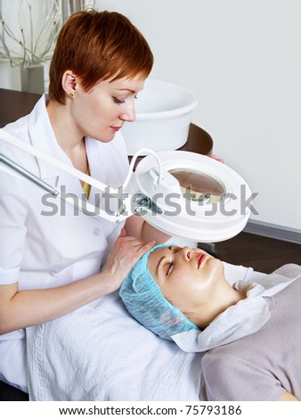 Doctor-cosmetologist examines woman skin