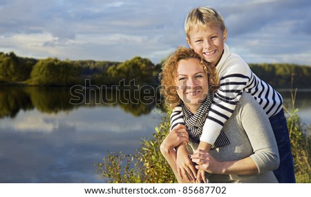 Mother and son near lake in evening glow