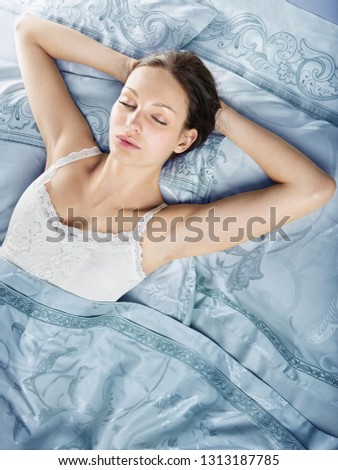 Beautiful young woman sleeping in luxury bed. Bed is made with linen embroidered percale.