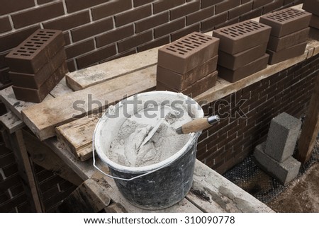 House under construction. Masonry cement and brown clinker bricks at scaffolding boards.
