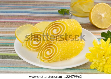 yellow candy fruit on a plate with lemon and flower