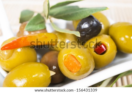 the stuffed olives with an olive branch lie on a plate, closeup