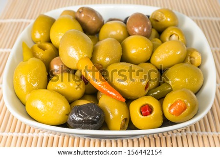Green olives stuffed with pepper, orange and garlic in a plate lie on a wooden background