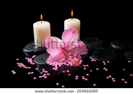 Beautiful spa still life of pink hibiscus, candles, zen stones with drops and pearl beads on reflection water