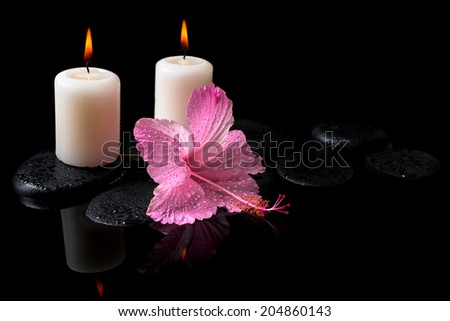Beautiful spa still life of delicate pink hibiscus, candles, zen stones with drops on reflection water