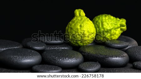 Aromatic spa concept of bergamot fruits on zen basalt black stones with dew