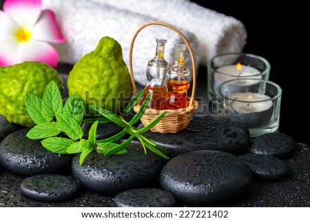 Aromatic concept of bergamot fruits, fresh mint, rosemary, candles, towels, flower and bottles essential oil on zen stones