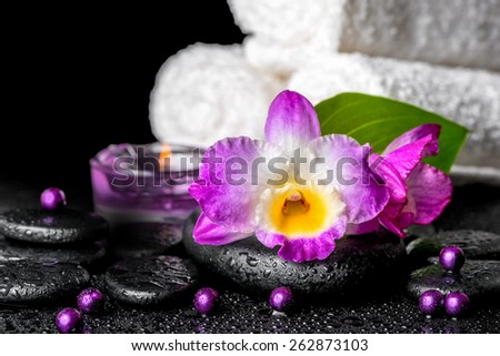 beautiful spa background of orchid dendrobium, green leaf, candles, white towels and beads on zen stones with drops
