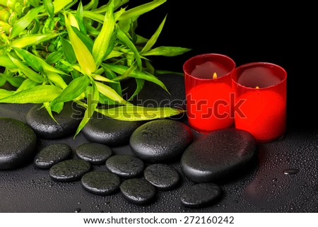 spa concept of twigs bamboo with dew and red candles on zen basalt stones