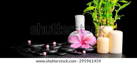 spa concept of hibiscus flower, bamboo, thai herbal compress ball, beads and candles on zen basalt stones with drops, panorama