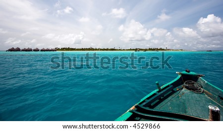 Boat going to the small tropical island in ocean visible at horizon