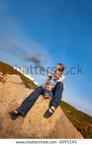 Family fun at Europe’s edge. Mother and son having fun together. Lighthouse of Cabo da Roca – west most point of Europe – is on background