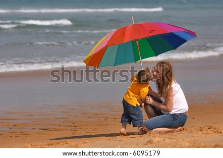 Don’t depend on weather conditions. Happy young woman and kid under brightly colored umbrella having fun outdoors.