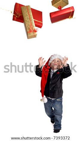 Gift rain. Small boy dressed in smart casual clothes and Santa hat trying to catch gift boxes.