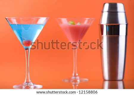 Colorful Mood. Betty Blue cocktail, Cosmopolitan cocktail and Shaker over colorful orange background.