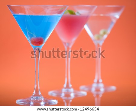Color in martini glass. Betty Blue cocktail, Cosmopolitan cocktail and Dry Martini over colorful orange background.
