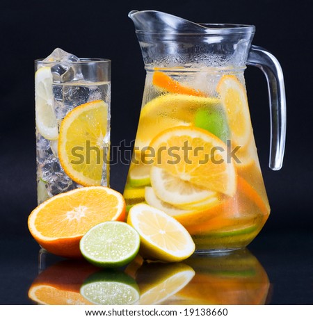 Citrus Ice Water. Citrus ice water glass and carafe over dark background