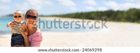 Young mother and baby girl on white sand tropical beach