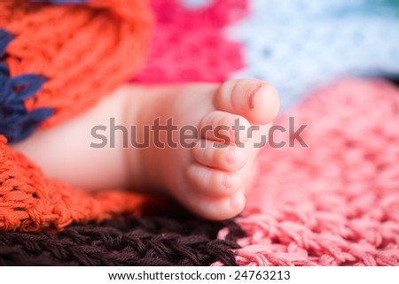 Feet of three months old baby covered with colorful blanket